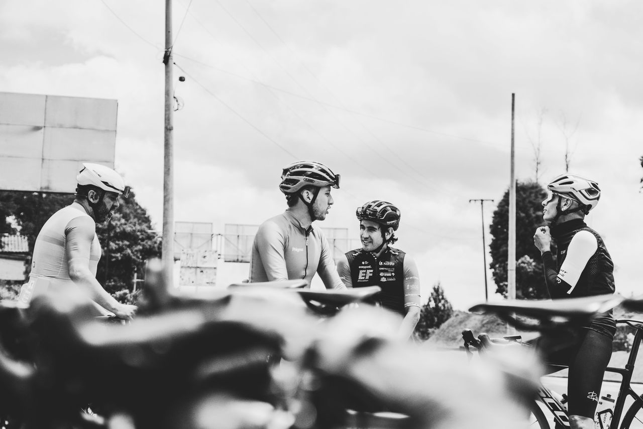 自転車のそばで話すサイクリストたちのモノクロ写真